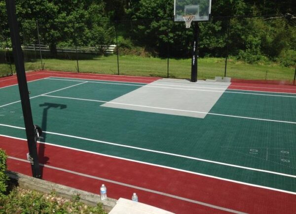 A tennis court with a net and basket ball hoop.